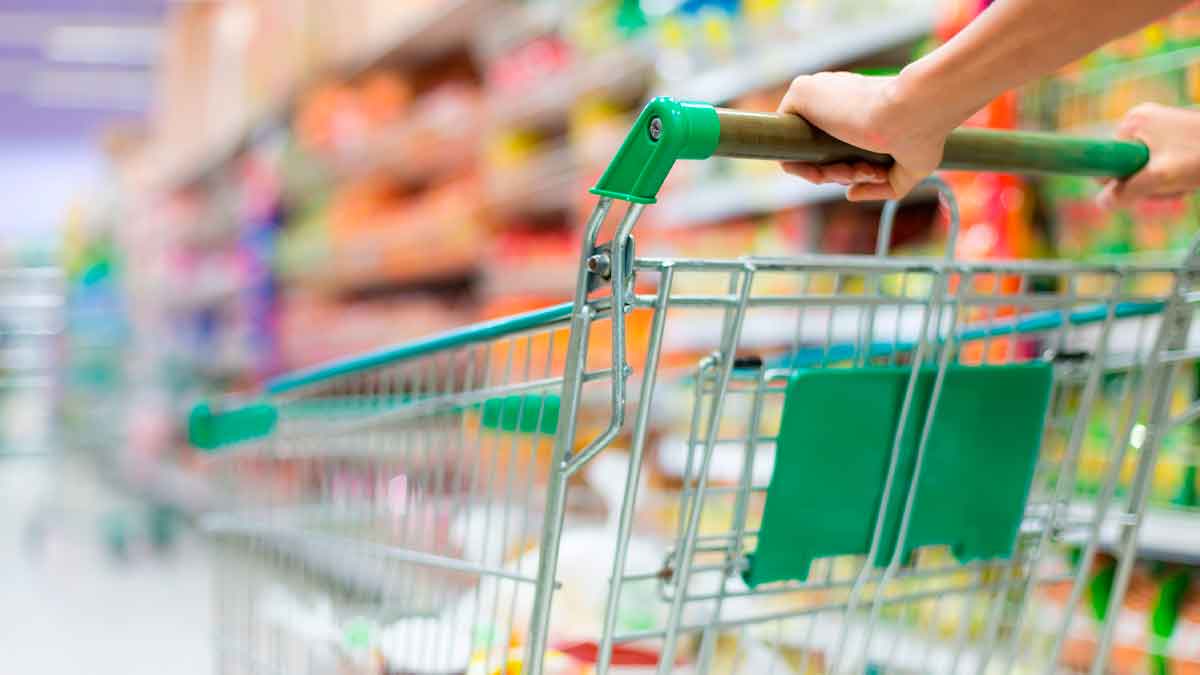 Carrito de la compra en un pasillo de supermercado vacío, clave para saber cuándo ir al supermercado y lograr los mayores descuentos