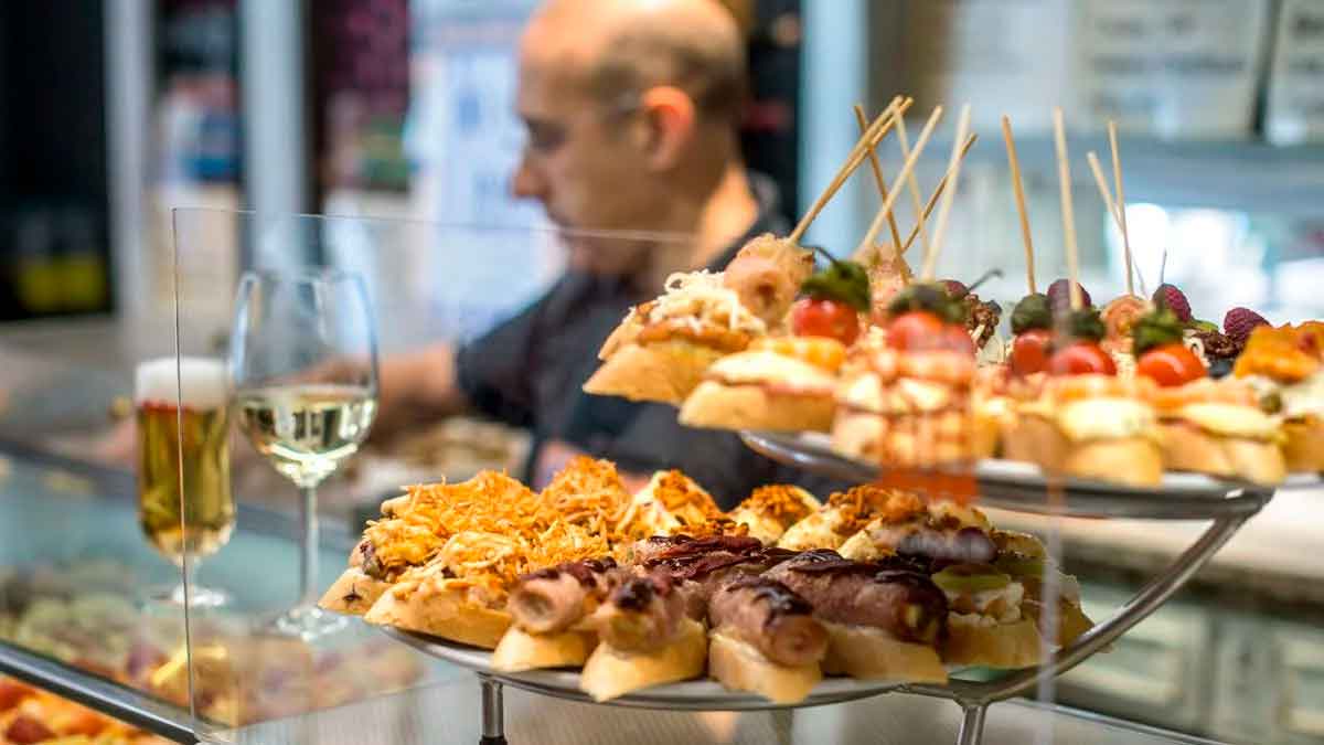 Bandeja de tapas variadas en un bar andaluz con copa de vino, escena clave de la ruta definitiva para tapear en Andalucía este verano