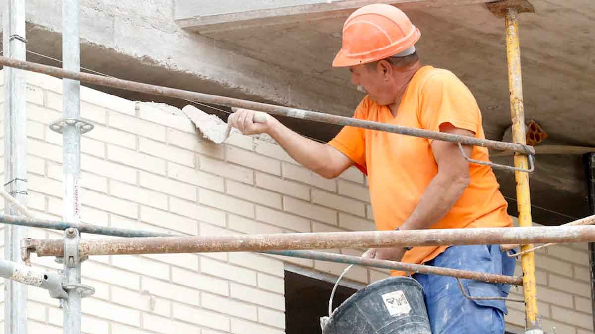 Albañil trabajando en la construcción, escasez de obreros y reducción de salarios en el sector de la construcción en España