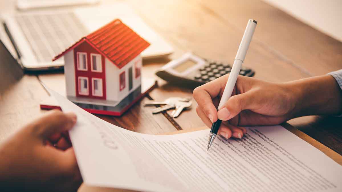 Firma de contrato de hipoteca con maqueta de casa, llaves y calculadora