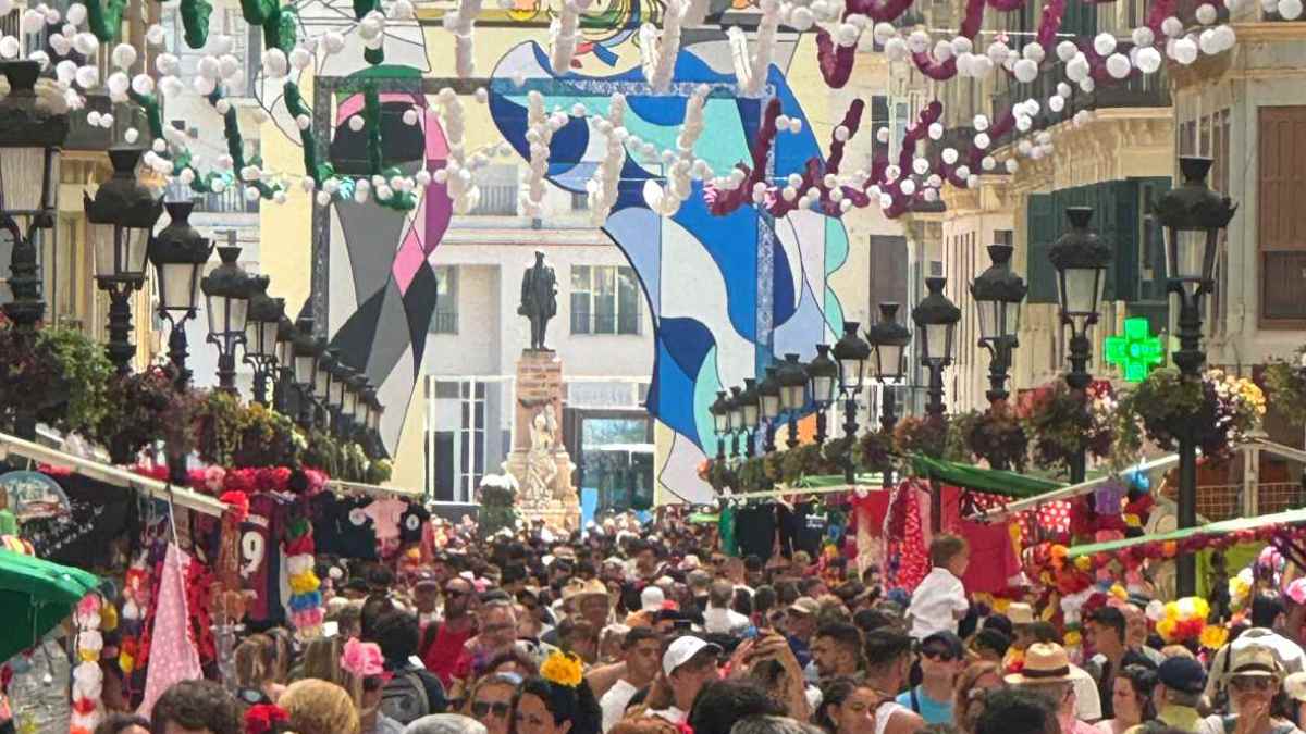 Calle Larios abarrotada y engalanada con farolillos durante la Feria de Málaga 2025 en horario de mediodía.