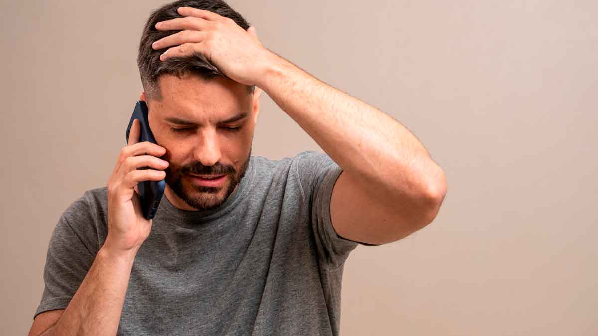 Hombre preocupado al recibir una llamada telefónica, preocupado por una posible estafa telefónica que pone en riesgo sus datos personales y bancarios