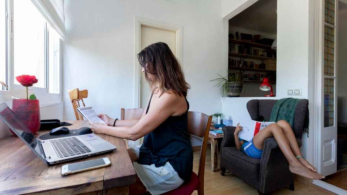 Funcionaria andaluza teletrabajando desde casa con portátil y documentos, nuevo decreto permite cuatro días remotos semanales en 2026