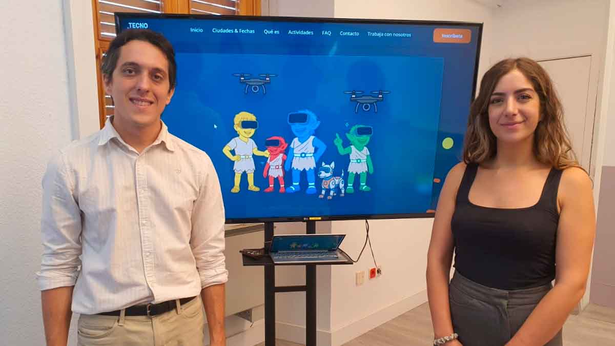 Presentación de Tecnotribu del Imefe en Jaén: dos responsables ante pantalla con personajes de realidad virtual y drones, campus digital gratuito para menores de 9-17 años