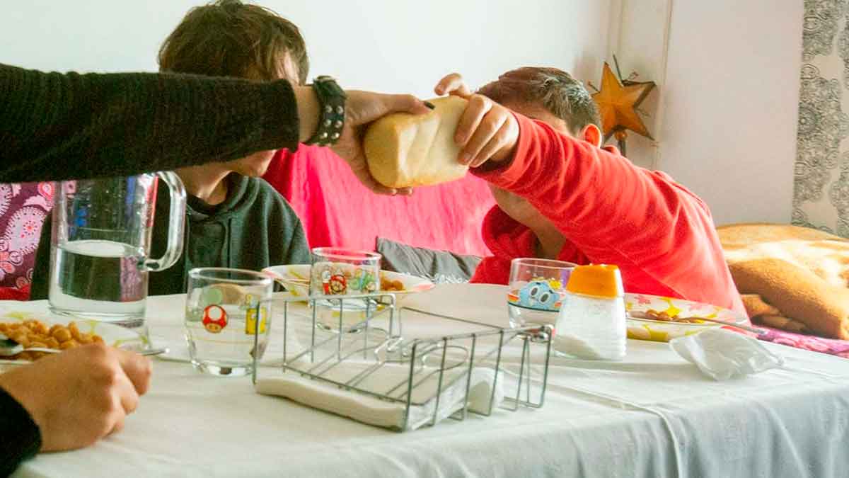Familia vulnerable comparte pan alrededor de la mesa en su hogar, representando a los hogares que aún no piden el Ingreso Mínimo Vital