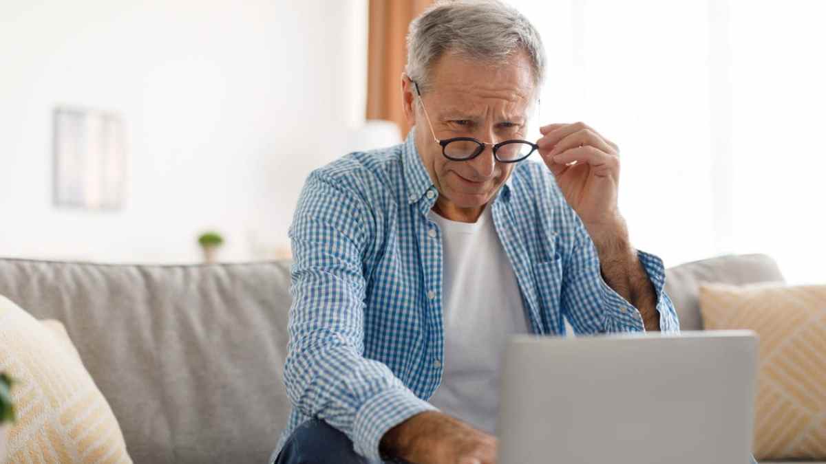 Hombre de 60 años consulta en su portátil los requisitos para jubilarse a los 63 con el 100 % de la pensión en 2025.