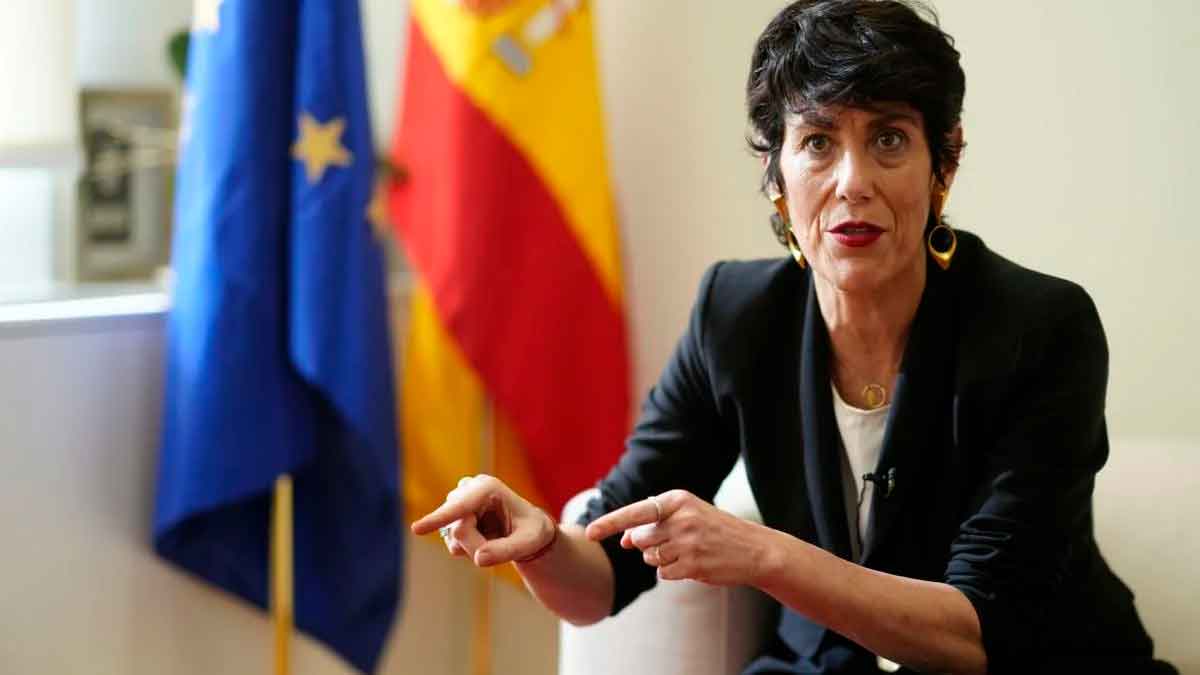 La ministra Elma Saiz explica la reforma de la jubilación anticipada con banderas de España y la UE al fondo, alusiva a la Ley 27/2011