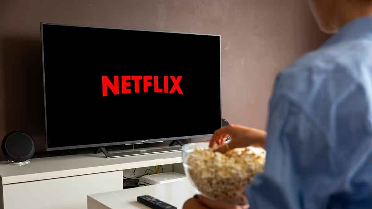 Persona con bol de palomitas viendo el logo de Netflix en la televisión, contexto del fin del Plan Básico sin anuncios