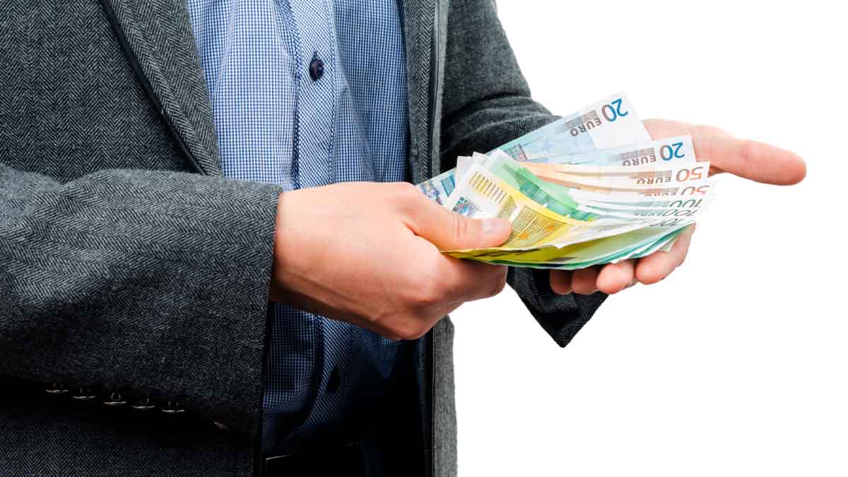 Persona pagando con billetes en efectivo, riesgo de multas por Hacienda durante las vacaciones de verano