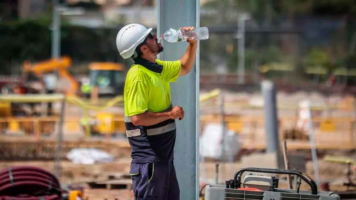 Trabajador de la construcción hidratándose durante ola de calor para cumplir con el Real Decreto 486/1997 sobre temperaturas máximas