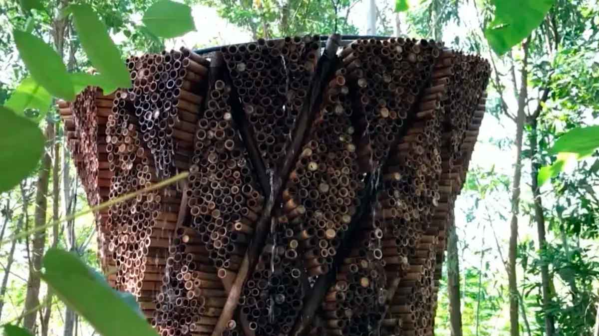 Torre de refrigeración adiabática hecha con tubos de bambú que deja caer agua para enfriar el aire en entornos naturales