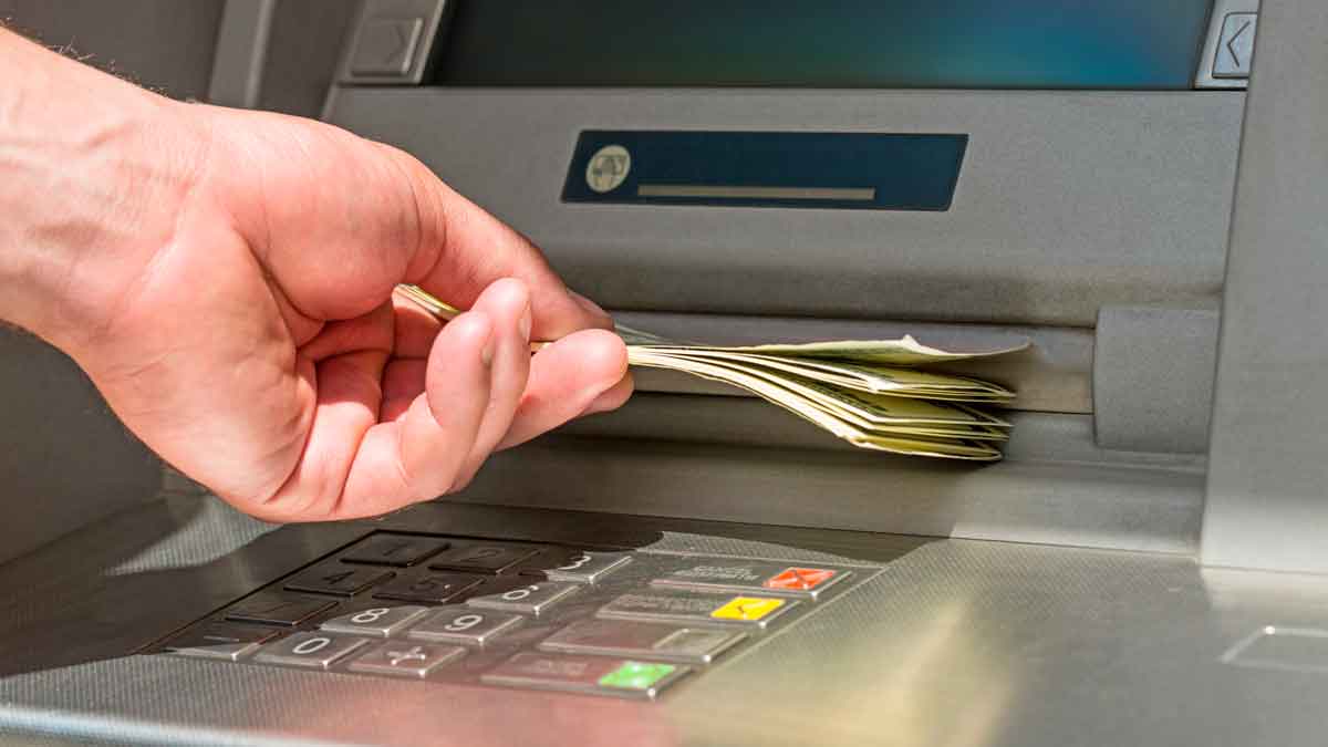 Mano retirando un fajo de billetes de un cajero automático, operación de más de 1.000 euros supervisada por Hacienda para evitar fraude fiscal
