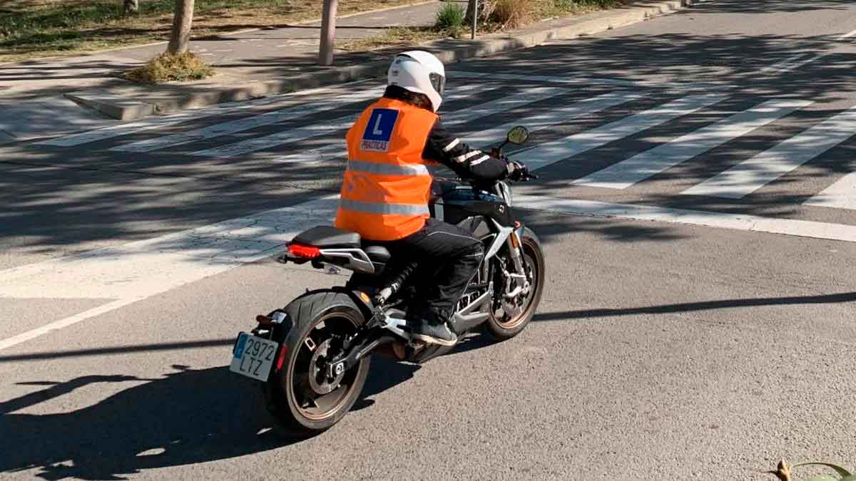 Alumno de autoescuela con chaleco reflectante y placa L practicando en moto por carretera para obtener el carnet A tras los nuevos requisitos de la DGT