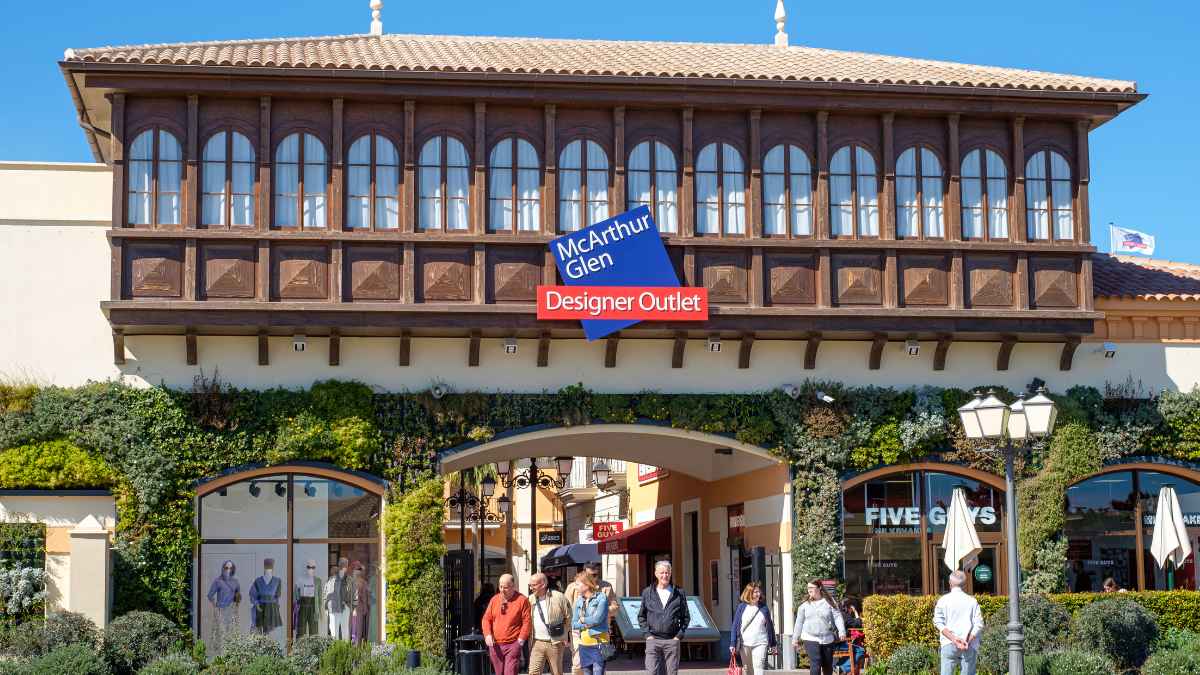 Entrada principal del centro comercial McArthurGlen Designer Outlet Málaga con clientes paseando