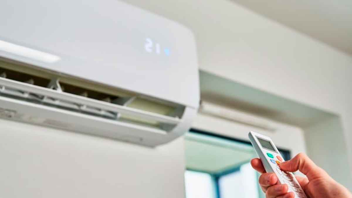 Persona usando control remoto del aire acondicionado para ahorrar energía mediante ajuste eficiente de temperatura con valor SEER
