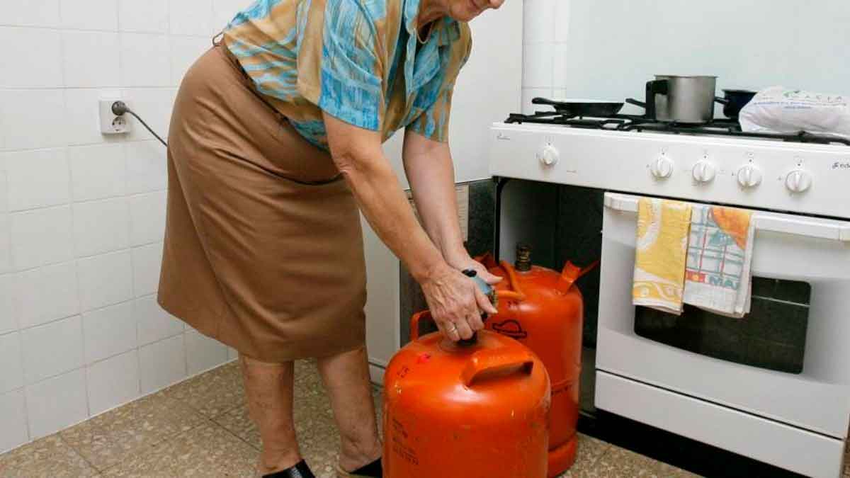 Mujer cambiando una bombona de butano en la cocina tras la última bajada de precios anunciada por el BOE