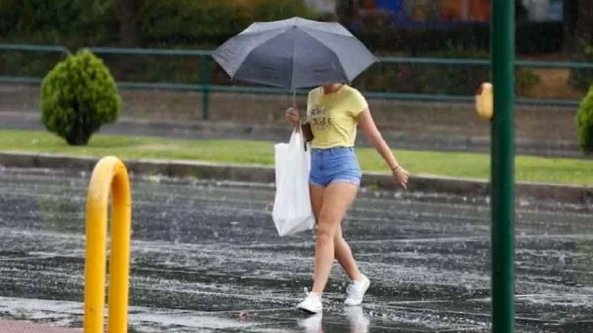 Mujer camina con paraguas bajo la lluvia durante tormenta en España por la llegada de una vaguada