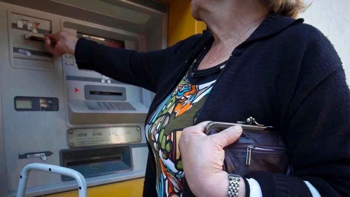 Pensionista retirando dinero del cajero automático por adelanto de pensiones en agosto 2025