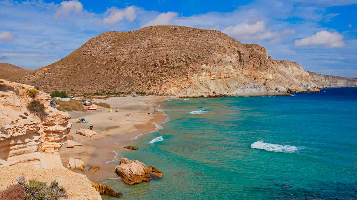Playa virgen de aguas turquesas en Cabo de Gata con arena dorada y acantilados