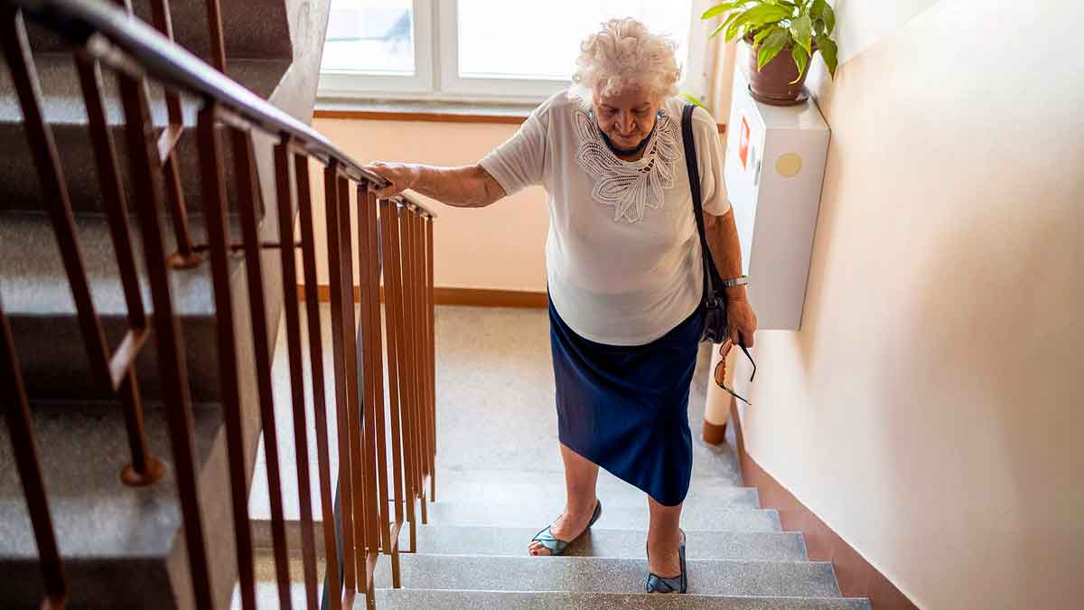 Mujer mayor subiendo escaleras en edificio sin ascensor en Sevilla
