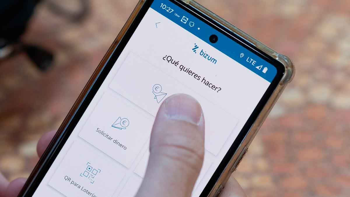 Persona usando Bizum en el móvil para enviar o recibir dinero con límites mensuales y control de Hacienda