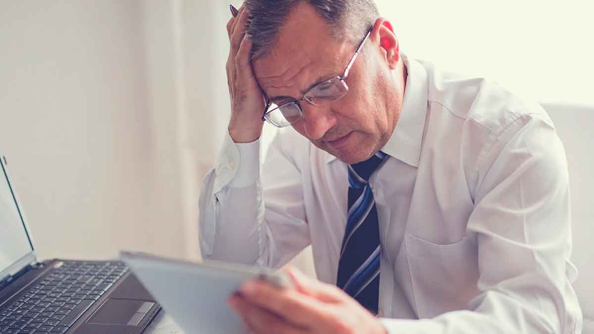 Hombre preocupado por embargo de cuenta bancaria revisando documentos financieros
