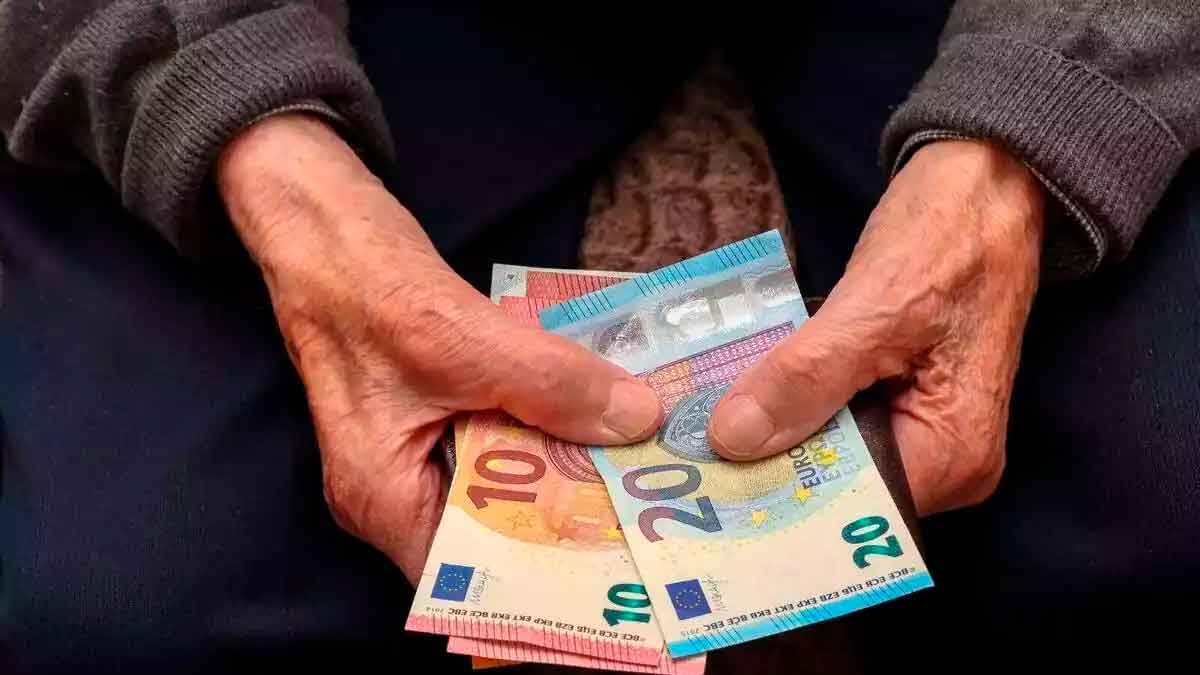 Manos de persona mayor contando billetes de 10 y 20 euros por devolución de Hacienda a mutualistas