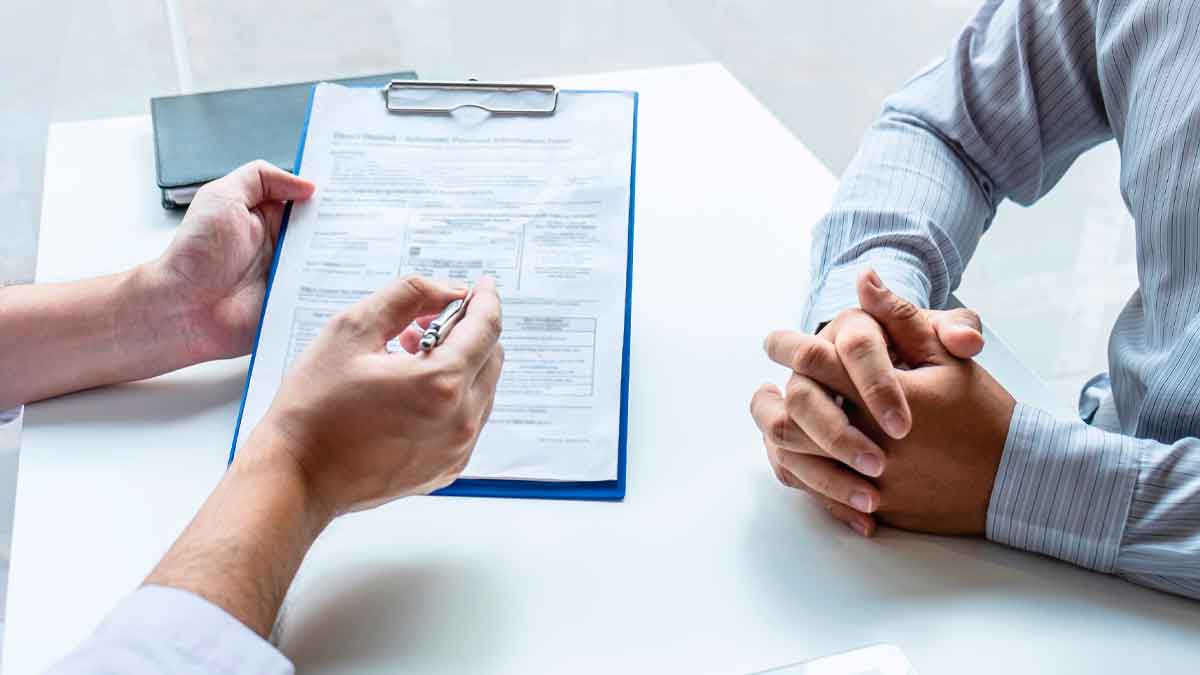 Médico explica el formulario de incapacidad permanente a un trabajador que agota la baja temporal.