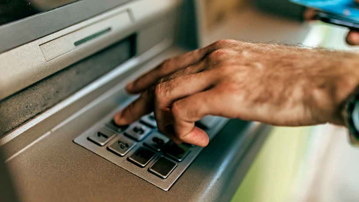 Persona ingresando dinero en un cajero automático con riesgo de billetes falsos según aviso del Banco de España