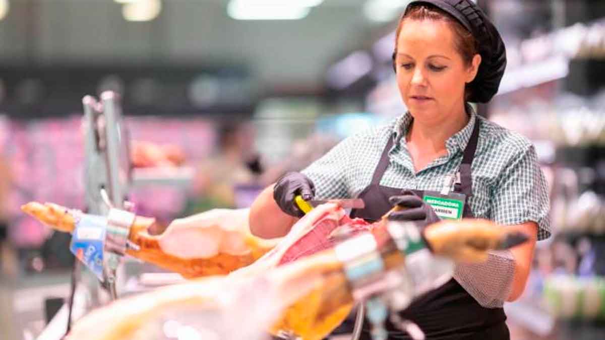 Empleada de Mercadona cortando jamón ibérico al corte de Jabugo en la sección de charcutería del supermercado