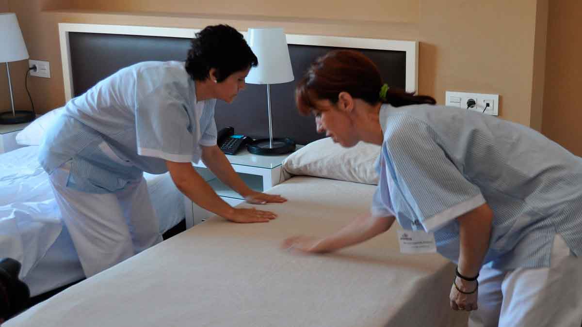 Dos trabajadoras camareras de piso haciendo una cama en hotel, ejemplo de sector feminizado para jubilación anticipada de mujeres