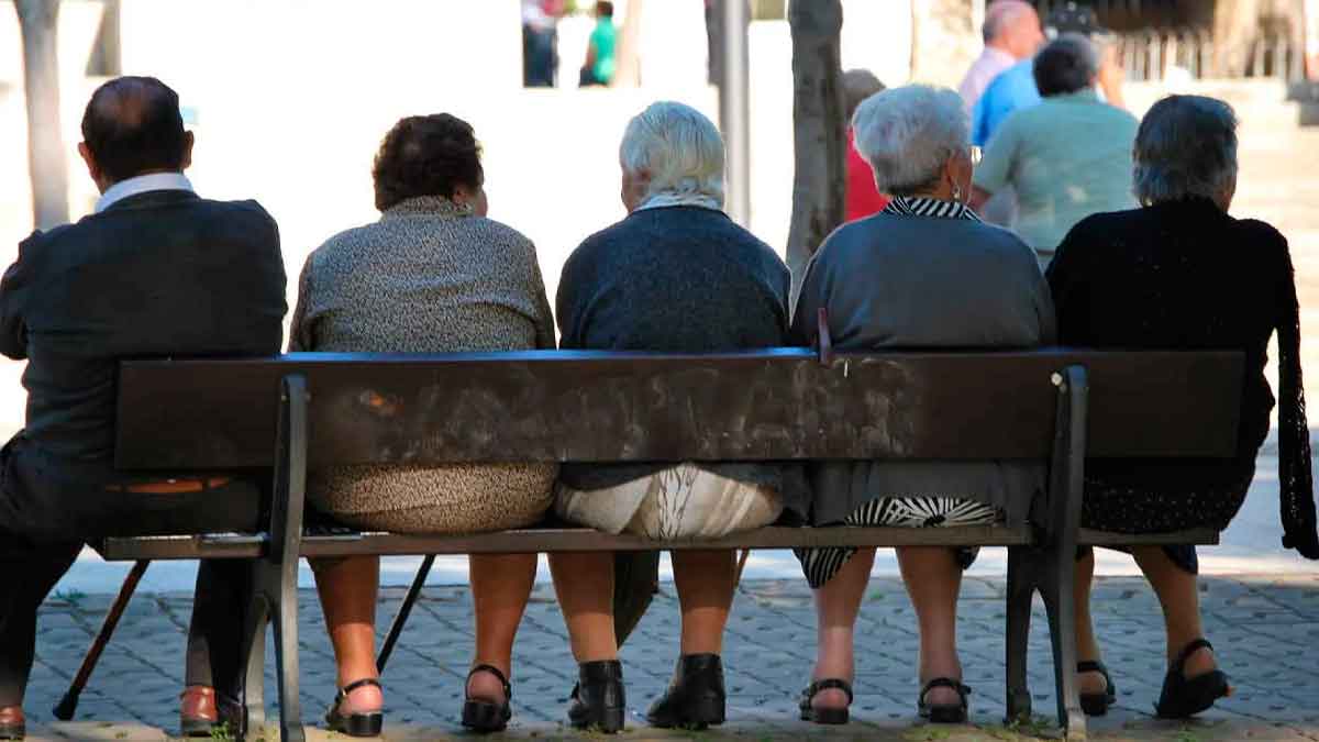 Personas mayores jubiladas sentadas en un banco al aire libre en España