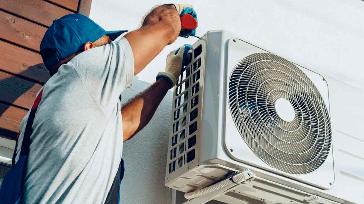 Técnico instalando unidad exterior de aire acondicionado en vivienda alquilada