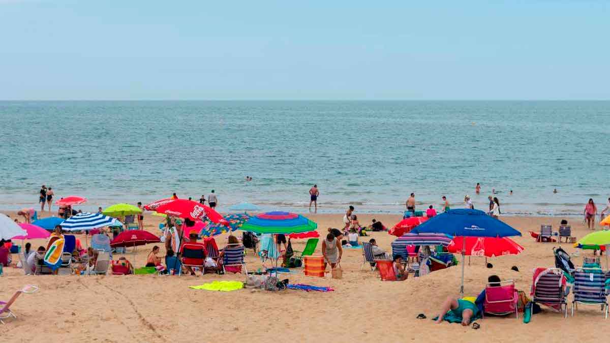 Sombrillas clavadas para reservar sitio en una playa andaluza concurrida, práctica sancionada con multas de hasta 750 euros
