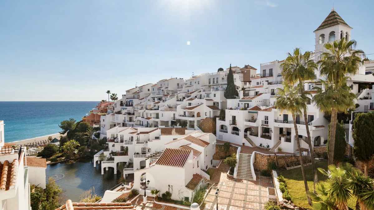 Panorámica de Nerja con casas blancas y balcones de geranios junto al Mediterráneo, nuevo destino veraniego de los madrileños