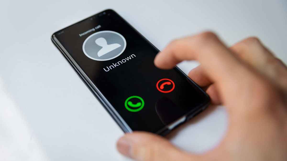 Mano atendiendo móvil con llamada desconocida; riesgo de estafa telefónica y clonación de voz