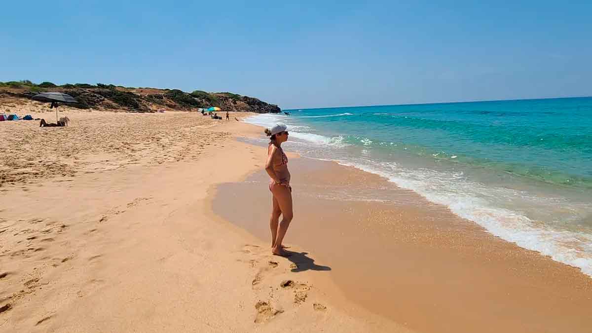 Mujer paseando por la orilla de playa virgen en el Parque Natural del Estrecho en Andalucía