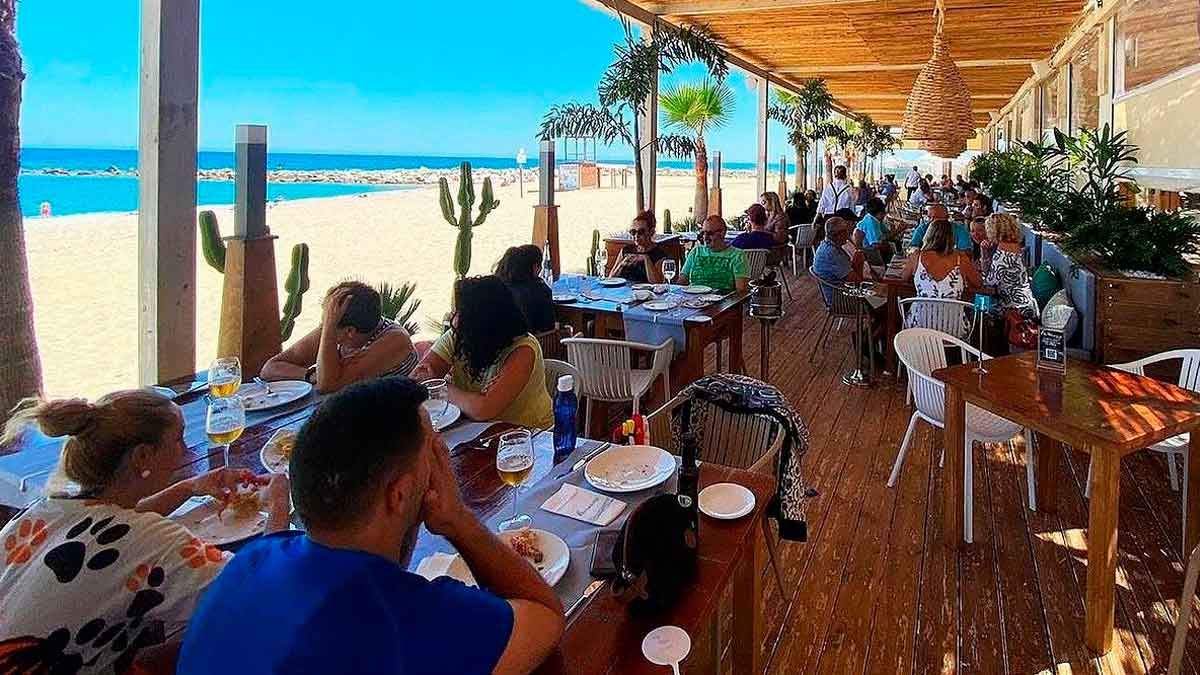 Comensales disfrutando del pescaíto frito en un chiringuito de playa en Andalucía durante el verano