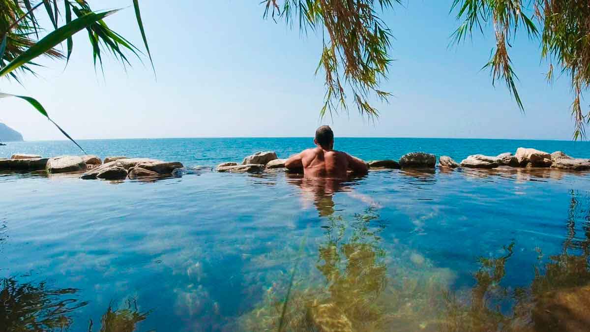 Hombre disfrutando de una piscina natural de agua dulce frente al mar en la playa Molino de Papel en Nerja, Málaga