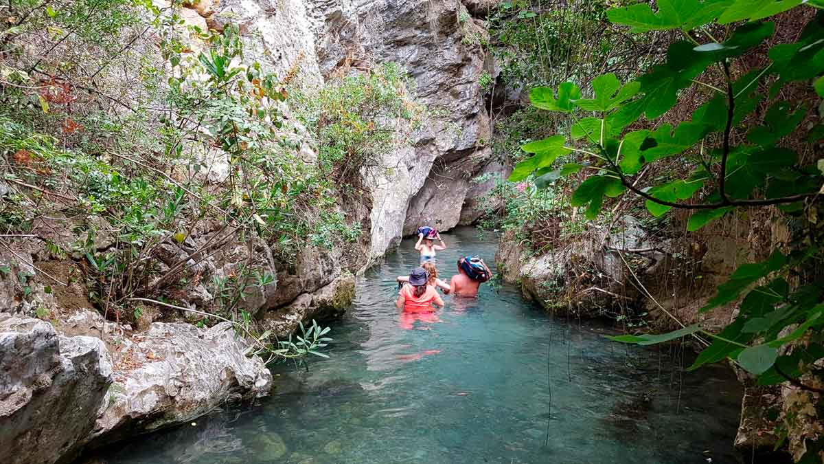 Personas recorriendo el sendero acuático del Arroyo Bocaleones en Andalucía entre aguas cristalinas y formaciones rocosas