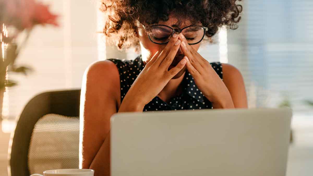 Mujer cansada frente al ordenador con síntomas del síndrome posvacacional