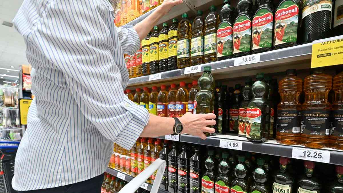 Cliente eligiendo aceite de oliva virgen extra en un supermercado con precios superiores a 4 euros