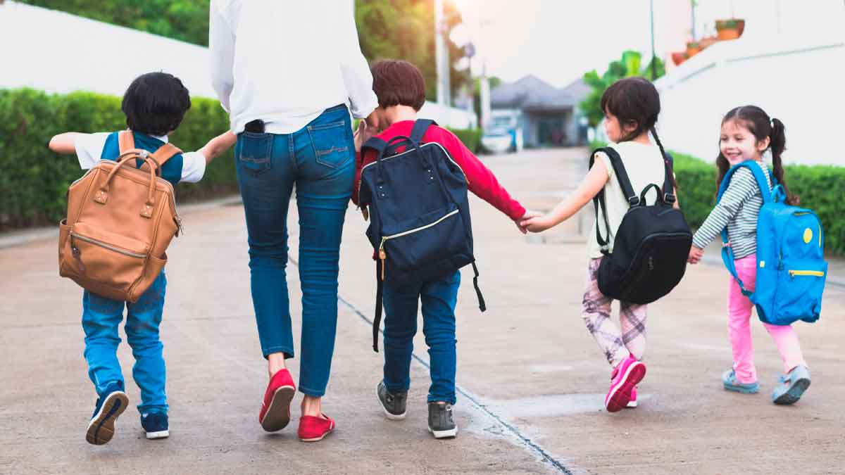 Niños con mochilas camino al colegio tras solicitar ayudas vuelta al cole Andalucía 2025-26.