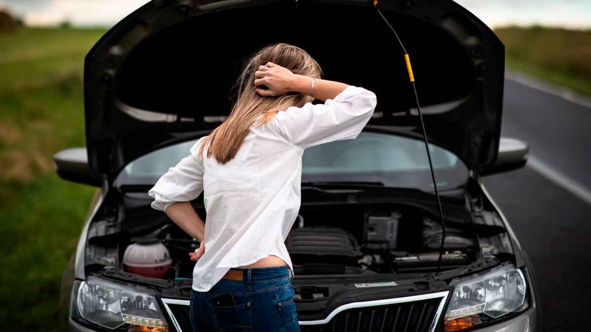 Mujer revisando coche averiado en carretera por fallo en frenos en España