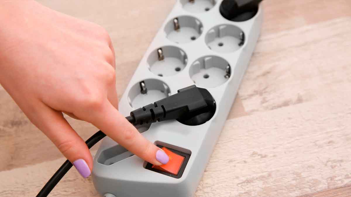 Mano encendiendo regleta electrica riesgo sobrecarga electrodomesticos hogar