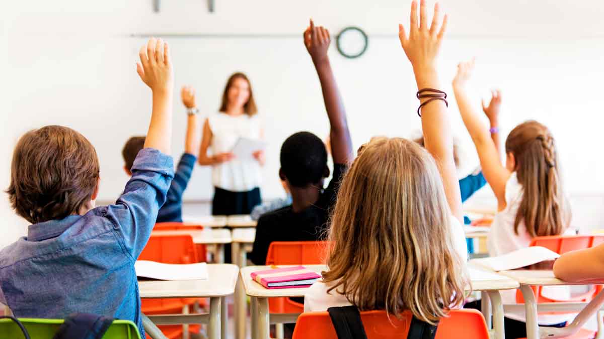 Niños en clase levantando la mano, gastos educativos deducción Andalucía renta 2025