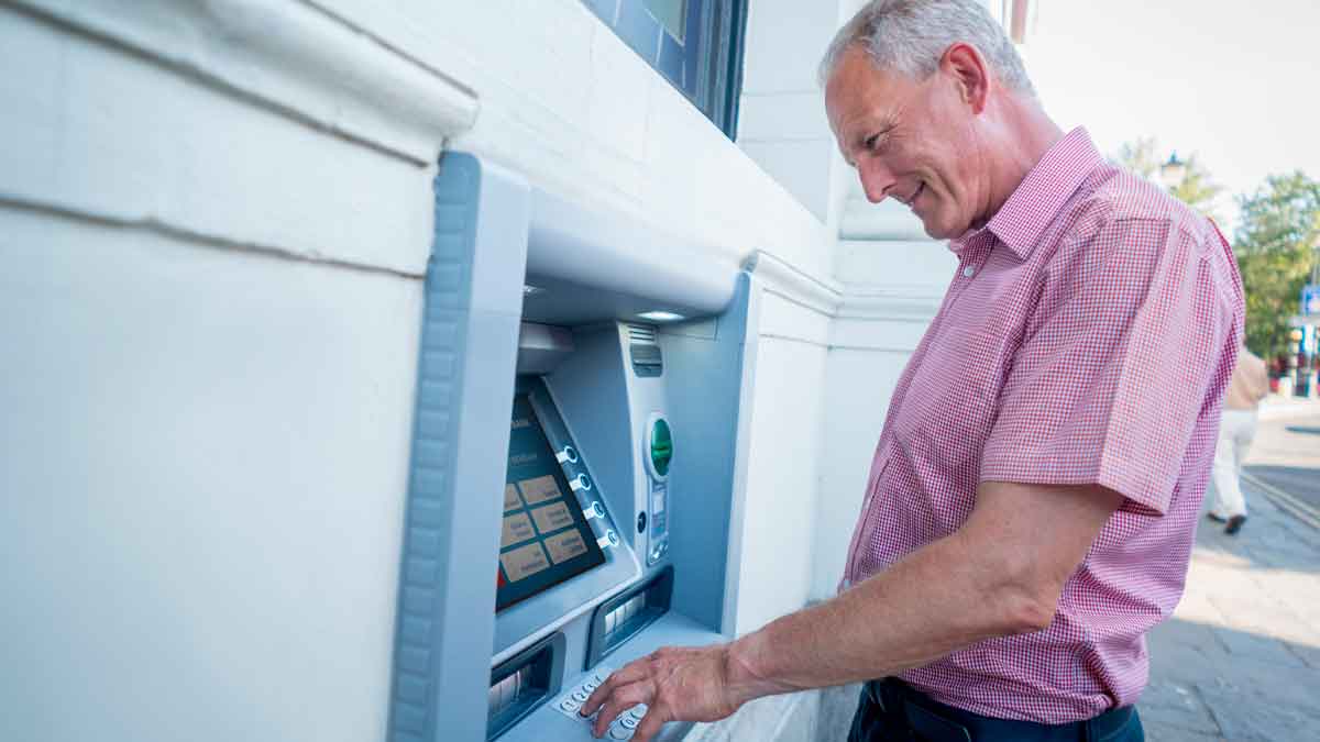 Hombre mayor retirando dinero de un cajero automático el día de cobro de pensiones en septiembre de 2025