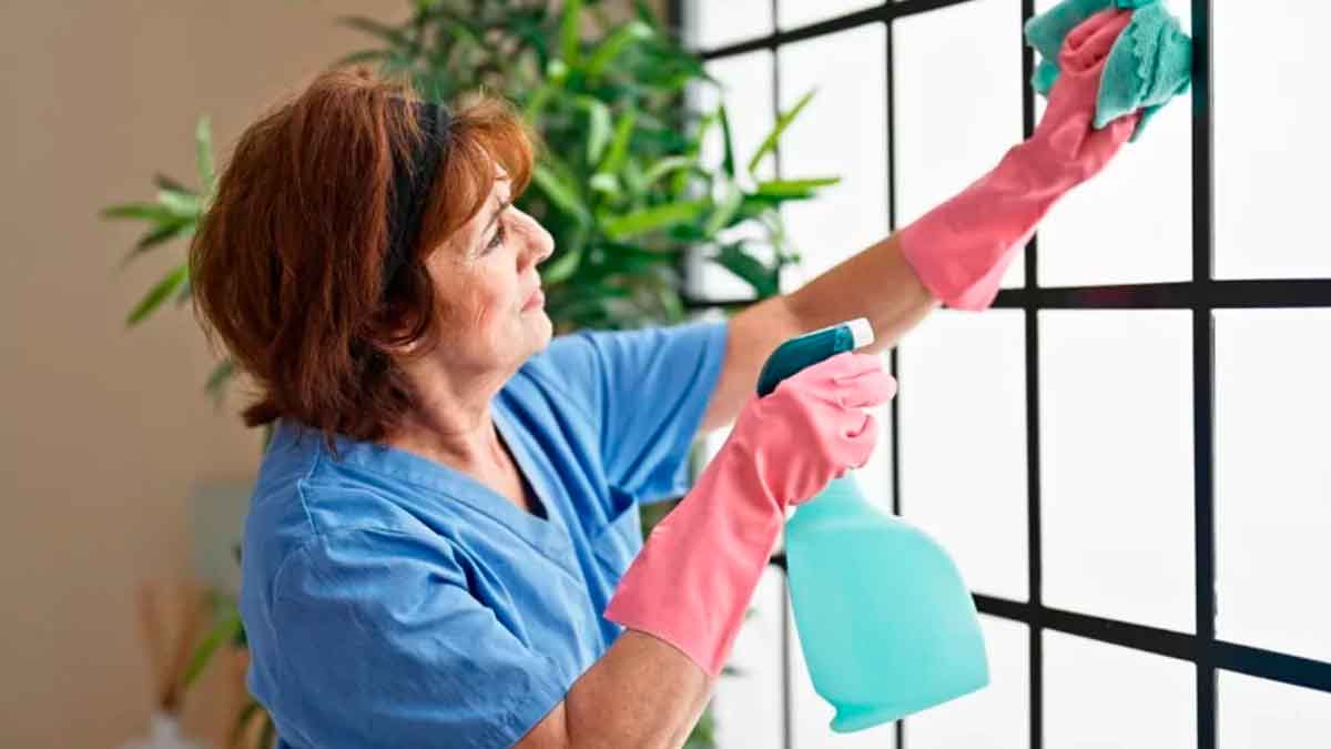 Empleada del hogar limpiando ventana como parte de la evaluación de riesgos laborales