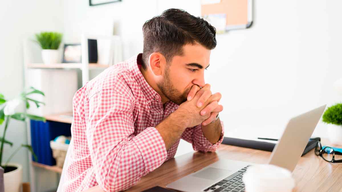 Joven preocupado frente al ordenador por el fin de la cuenta bancaria gratuita con comisiones