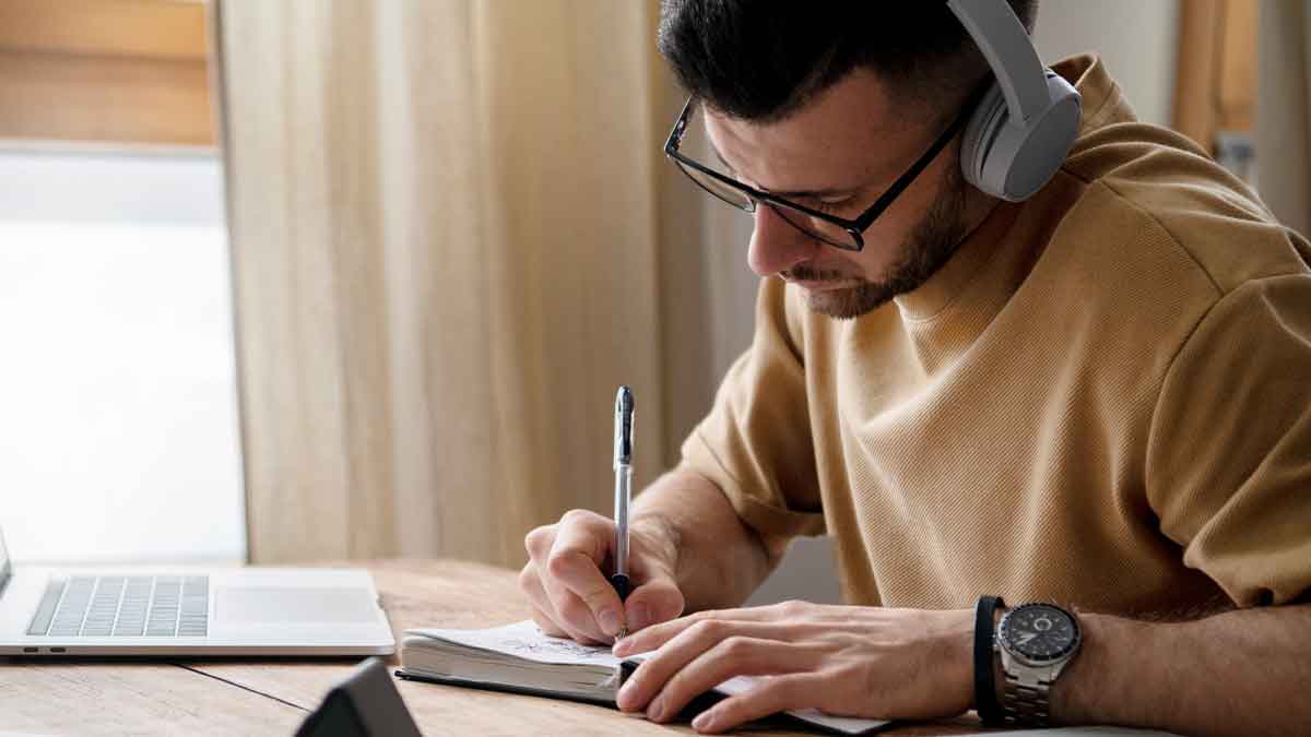 Estudiante con auriculares tomando apuntes mientras estudia FP oficial a distancia en casa